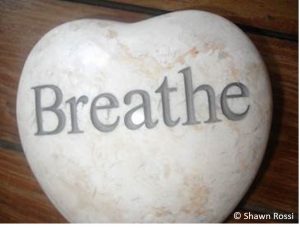 A picture of a heart-shaped stone with the word breathe written on it