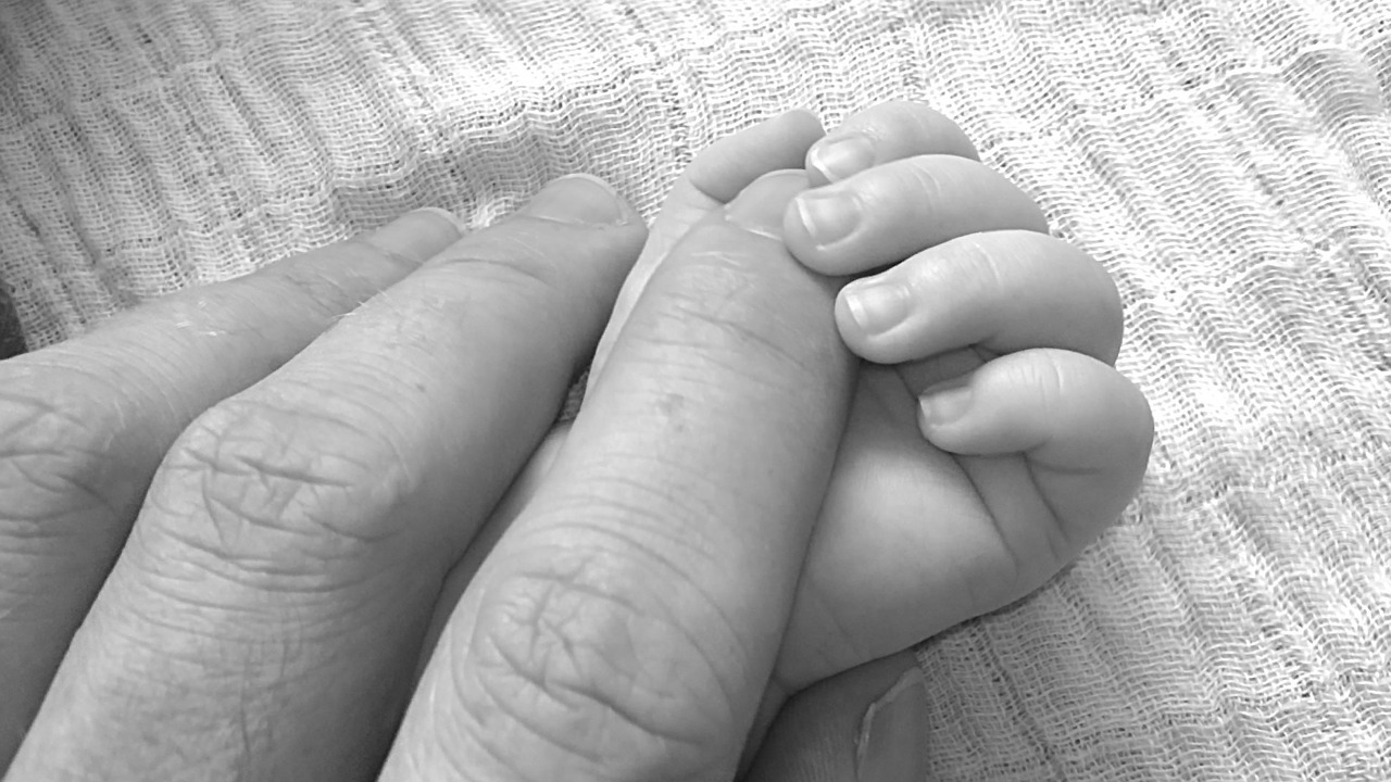 A baby's hand holding Mum's fingers
